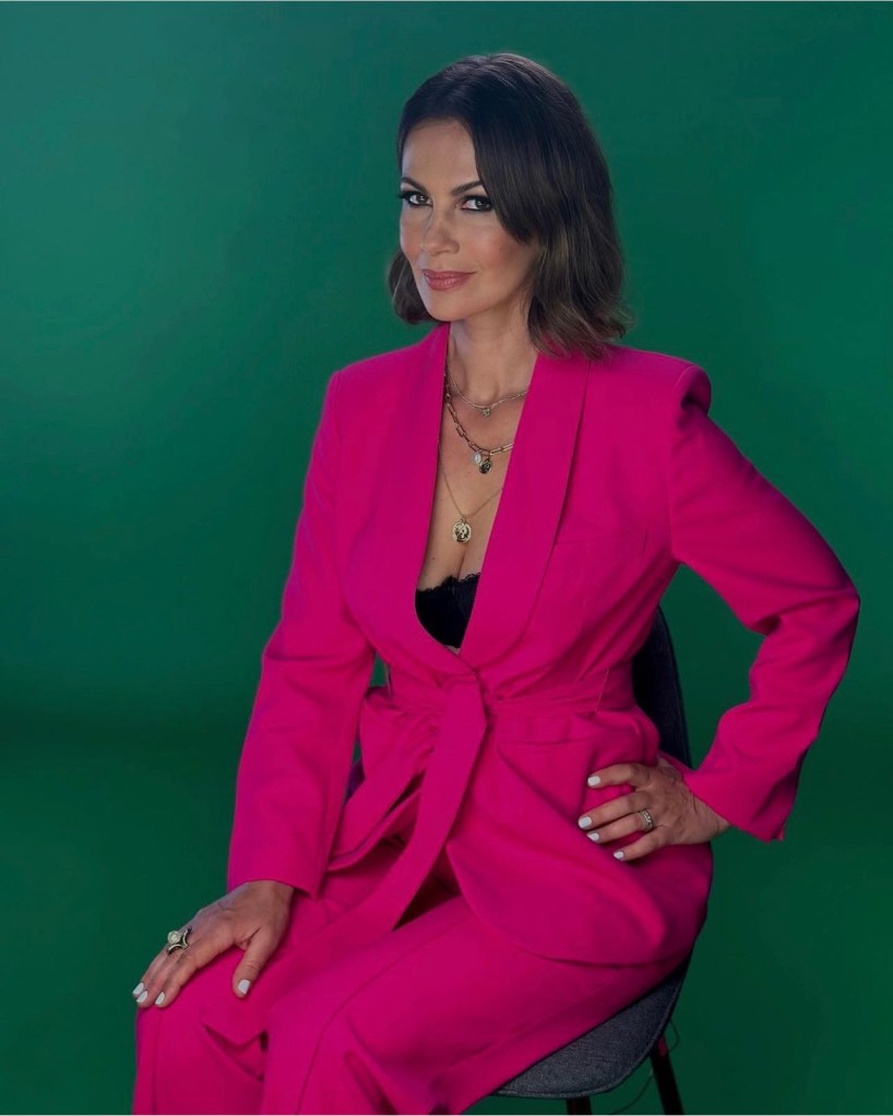 Julia Lemigova poses with hand on her hip while wearing pink suit for RHOM confessional interview
