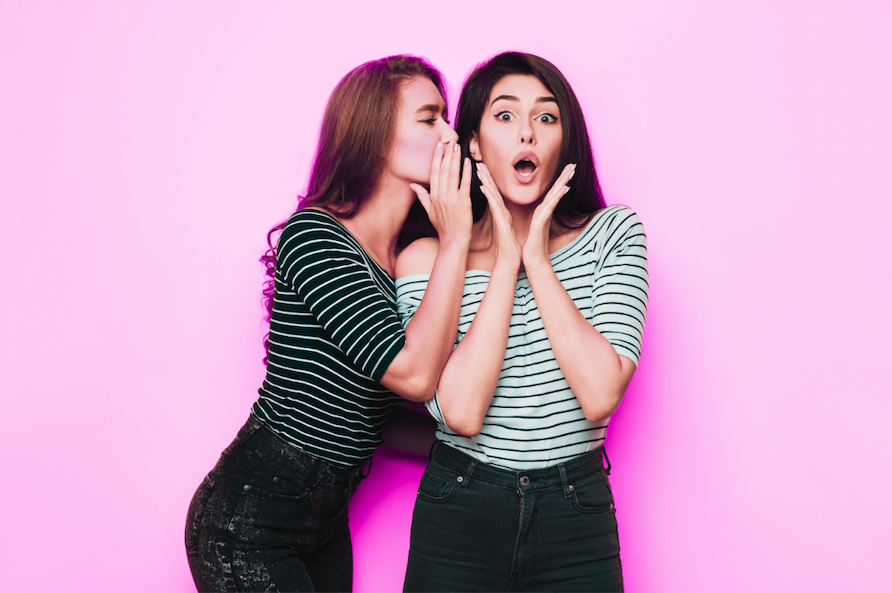two girls gossiping while wearing matching black and white striped shirts